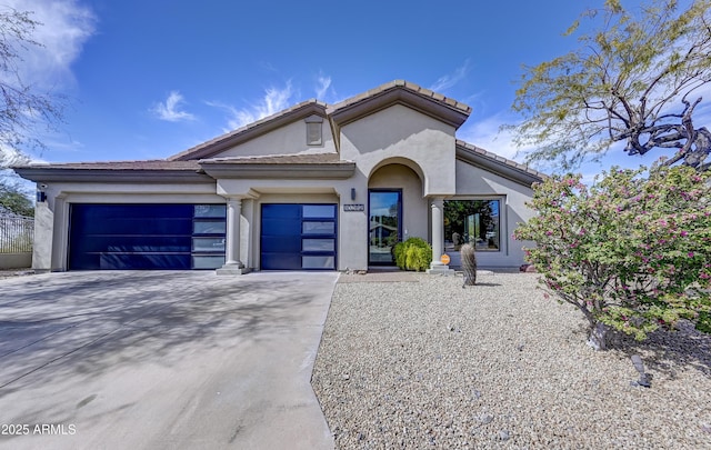 view of front of house with a garage, concrete driveway, a tiled roof, and stucco siding