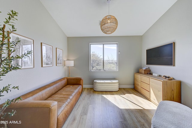 living room featuring light wood finished floors, baseboards, and vaulted ceiling