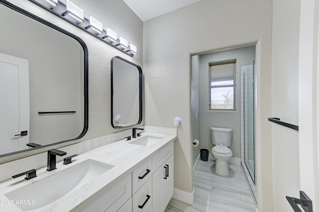 full bath featuring baseboards, a sink, toilet, and double vanity