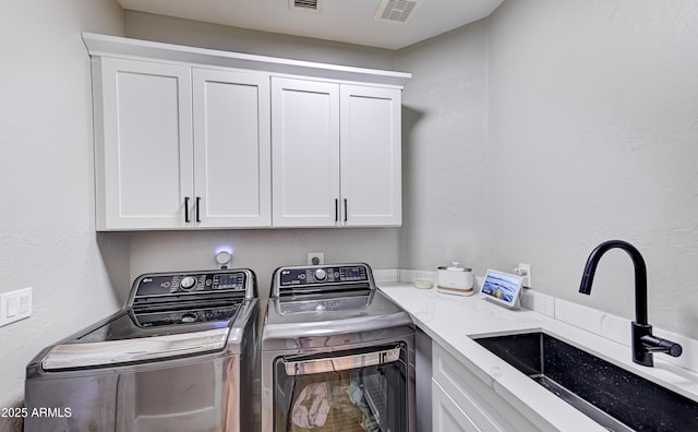 clothes washing area featuring visible vents, independent washer and dryer, a sink, and cabinet space