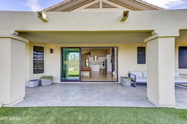 view of exterior entry featuring visible vents, a patio, a tiled roof, and stucco siding