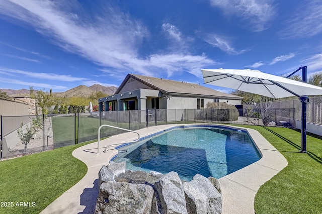 view of swimming pool featuring a fenced backyard, a mountain view, a fenced in pool, and a yard