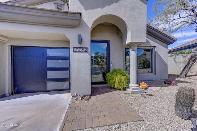 doorway to property featuring driveway, a tile roof, and stucco siding