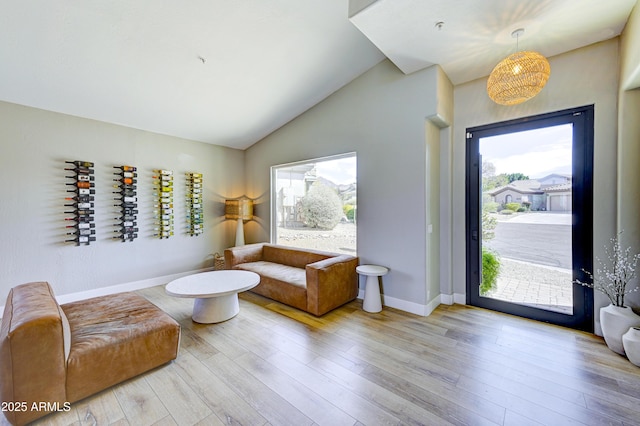 interior space with light wood-style floors, vaulted ceiling, and baseboards