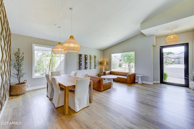 dining room featuring vaulted ceiling, light wood-type flooring, and baseboards