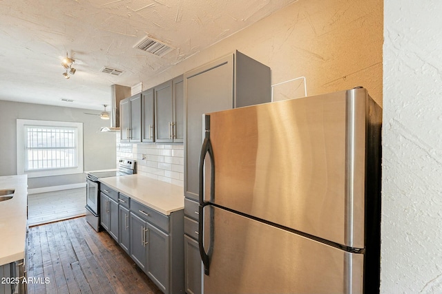 kitchen with backsplash, dark hardwood / wood-style floors, gray cabinets, and stainless steel appliances