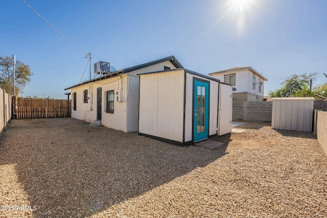 rear view of property featuring a shed and central air condition unit