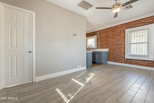 unfurnished living room with ceiling fan and brick wall