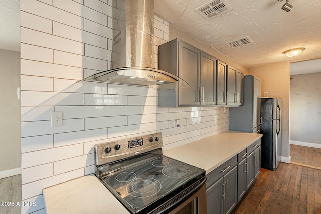 kitchen featuring appliances with stainless steel finishes, wall chimney exhaust hood, backsplash, and dark hardwood / wood-style flooring