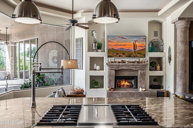 kitchen featuring ceiling fan, built in features, stone counters, and decorative columns