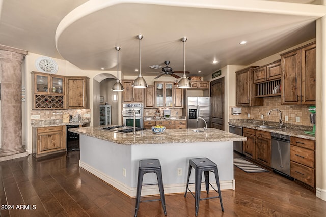 kitchen with sink, hanging light fixtures, dark hardwood / wood-style flooring, a kitchen island with sink, and appliances with stainless steel finishes