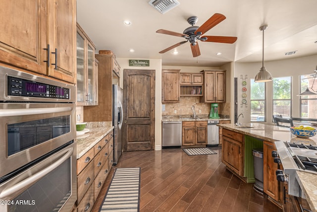 kitchen with appliances with stainless steel finishes, dark hardwood / wood-style flooring, backsplash, light stone counters, and pendant lighting