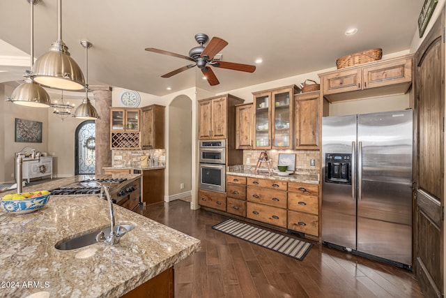 kitchen featuring light stone countertops, appliances with stainless steel finishes, dark hardwood / wood-style flooring, tasteful backsplash, and pendant lighting