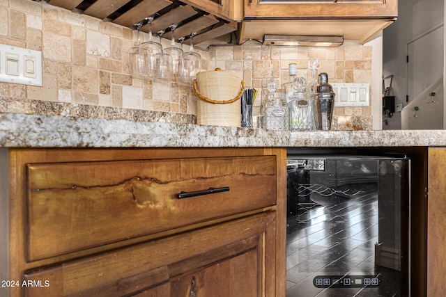 interior space featuring backsplash, wine cooler, and light stone countertops