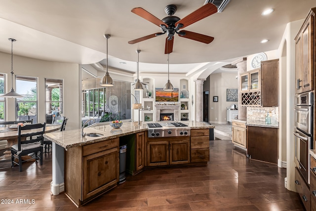 kitchen with pendant lighting, dark hardwood / wood-style flooring, light stone countertops, and appliances with stainless steel finishes