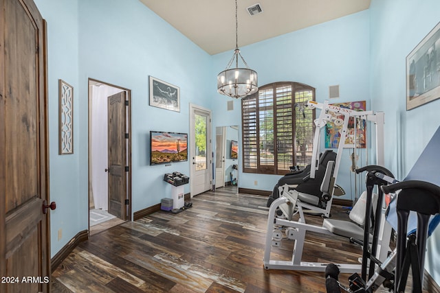 workout room with a chandelier, a high ceiling, and dark hardwood / wood-style floors