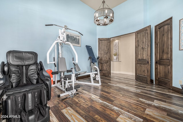 exercise room featuring high vaulted ceiling, dark wood-type flooring, and a notable chandelier