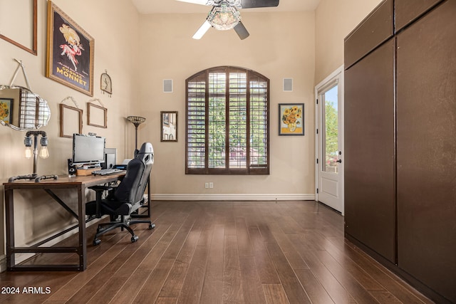 office area with ceiling fan, dark wood-type flooring, and a high ceiling