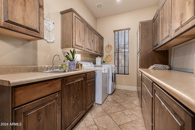 clothes washing area with separate washer and dryer, sink, and cabinets