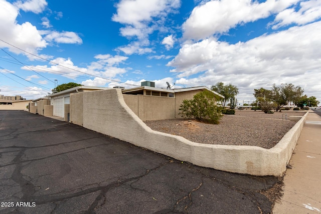 view of property exterior featuring stucco siding, fence, and community garages