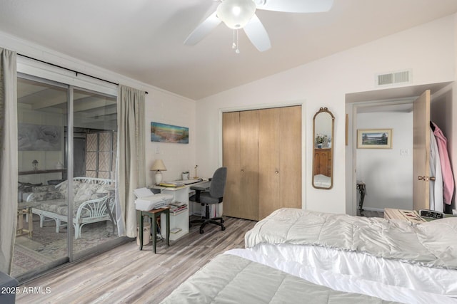 bedroom featuring ceiling fan, wood finished floors, visible vents, vaulted ceiling, and a closet