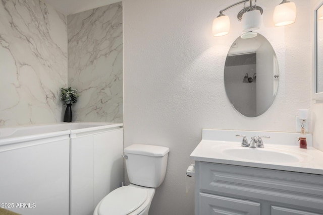 bathroom with toilet, a textured wall, and vanity