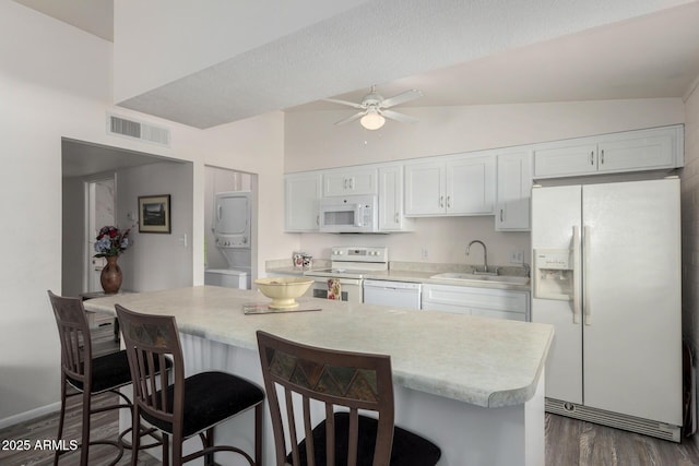 kitchen with white appliances, visible vents, lofted ceiling, light countertops, and stacked washing maching and dryer