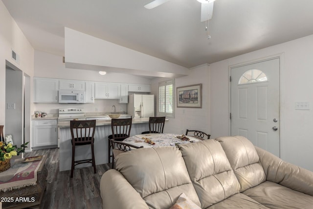 living area with vaulted ceiling, ceiling fan, dark wood-style floors, and visible vents