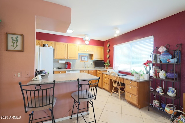 kitchen featuring tasteful backsplash, sink, a kitchen breakfast bar, light tile patterned floors, and white appliances