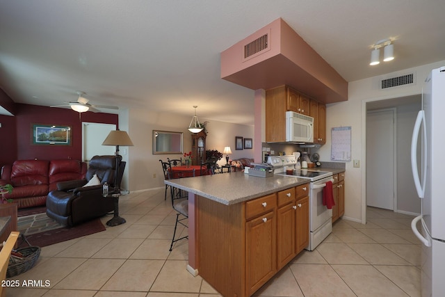 kitchen featuring light tile patterned flooring, a kitchen bar, kitchen peninsula, pendant lighting, and white appliances