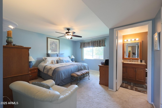 bedroom with ceiling fan, connected bathroom, sink, and light carpet