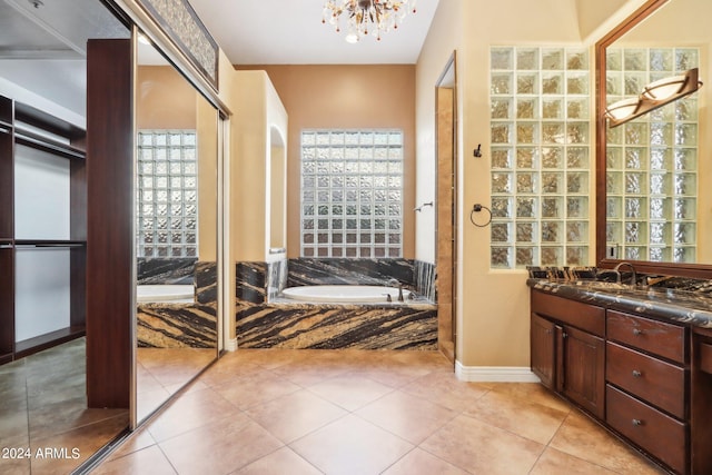 bathroom with vanity, a chandelier, tile patterned flooring, and a bathing tub