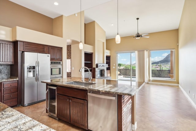 kitchen with appliances with stainless steel finishes, sink, backsplash, wine cooler, and a center island with sink