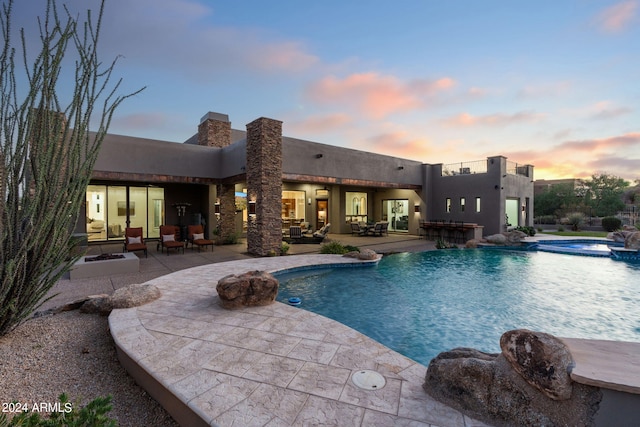 pool at dusk with an outdoor living space and a patio area