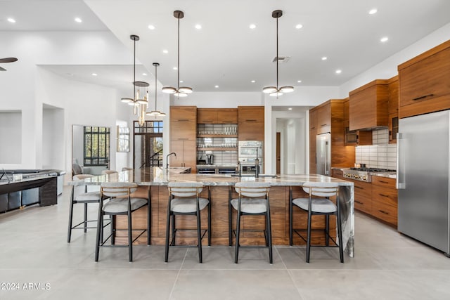 kitchen with a spacious island, decorative light fixtures, stainless steel appliances, and a kitchen bar