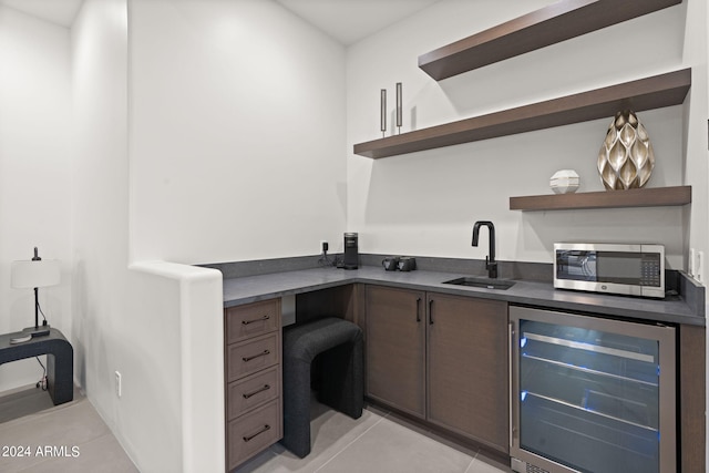 interior space with dark brown cabinetry, light tile patterned floors, beverage cooler, and sink