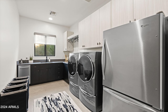 laundry area with cabinets, sink, light tile patterned flooring, and washing machine and dryer