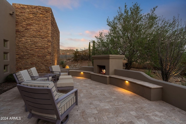 patio terrace at dusk with an outdoor stone fireplace