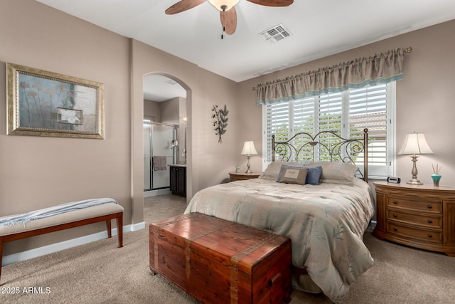 bedroom with ceiling fan, ensuite bathroom, and light carpet