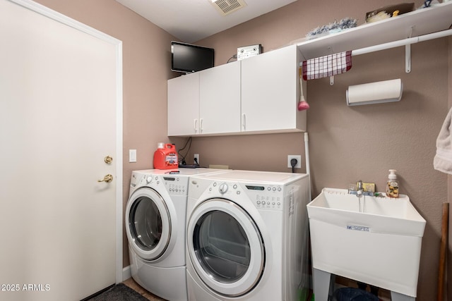 clothes washing area with cabinets, sink, and washing machine and dryer