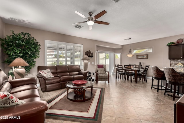 tiled living room with ceiling fan and a textured ceiling