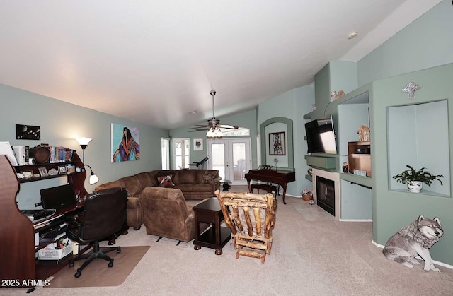 carpeted living room with french doors, a tiled fireplace, ceiling fan, and vaulted ceiling