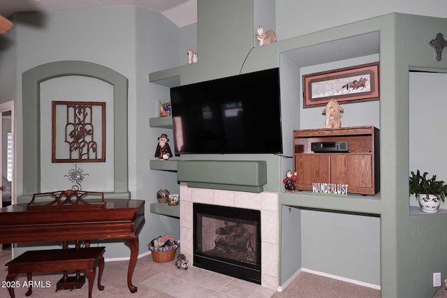 living room featuring a tiled fireplace and light tile patterned floors