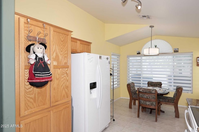 kitchen featuring vaulted ceiling, light brown cabinets, white appliances, light tile patterned flooring, and hanging light fixtures