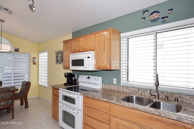 kitchen with white appliances, hanging light fixtures, light tile patterned floors, dark stone counters, and sink