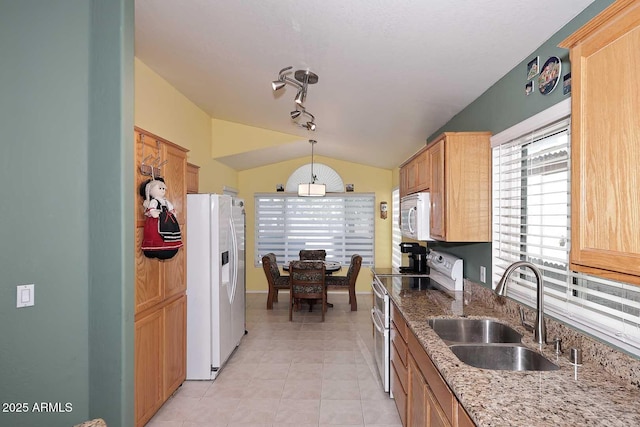 kitchen with white appliances, hanging light fixtures, light stone countertops, sink, and lofted ceiling