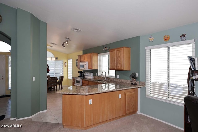 kitchen featuring white appliances, kitchen peninsula, hanging light fixtures, plenty of natural light, and sink