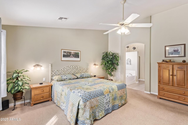 bedroom featuring lofted ceiling, connected bathroom, light colored carpet, and ceiling fan