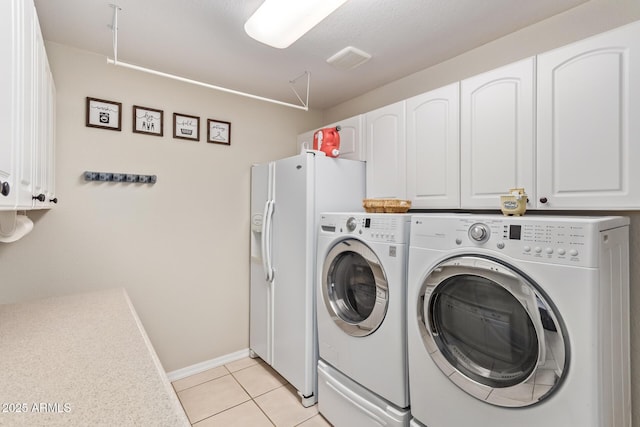 washroom featuring light tile patterned flooring, cabinets, and washer and dryer