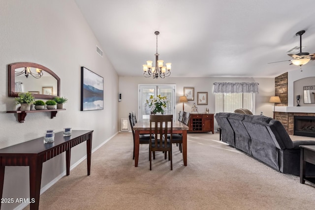 dining room with a fireplace, ceiling fan with notable chandelier, vaulted ceiling, and light colored carpet